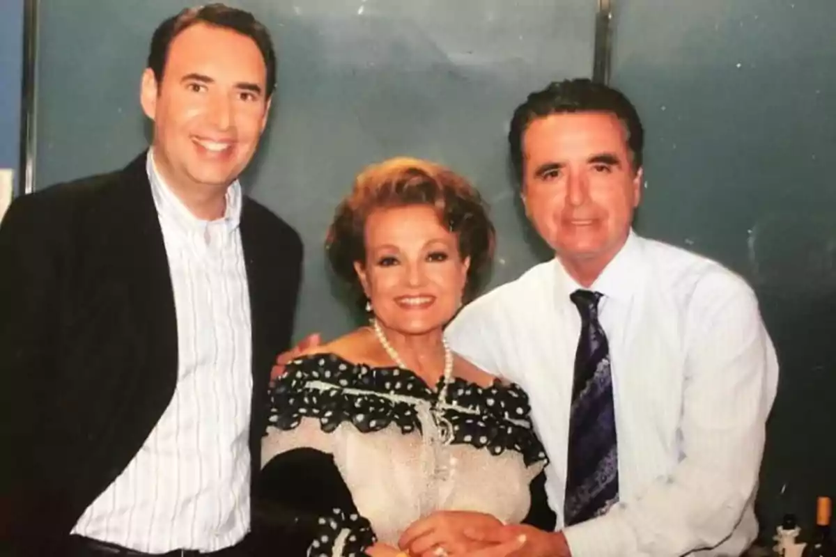 Tres personas posan sonrientes para la cámara, dos hombres y una mujer en el centro, todos vestidos de manera formal Tres personas posan sonrientes para la cámara, dos hombres y una mujer en el centro, todos vestidos de manera formal