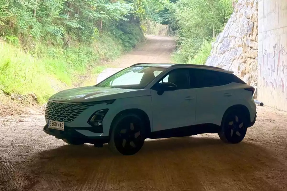 OMODA 5 SUV blanco estacionado en un camino de tierra bajo un puente rodeado de vegetación y árboles OMODA 5 SUV blanco estacionado en un camino de tierra bajo un puente rodeado de vegetación y árboles