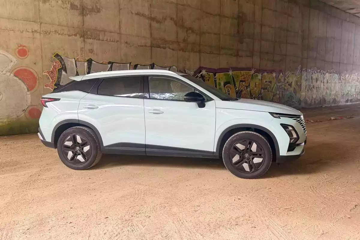 SUV OMODA 5 blanca estacionada bajo un puente con paredes cubiertas de grafitis SUV OMODA 5 blanca estacionada bajo un puente con paredes cubiertas de grafitis