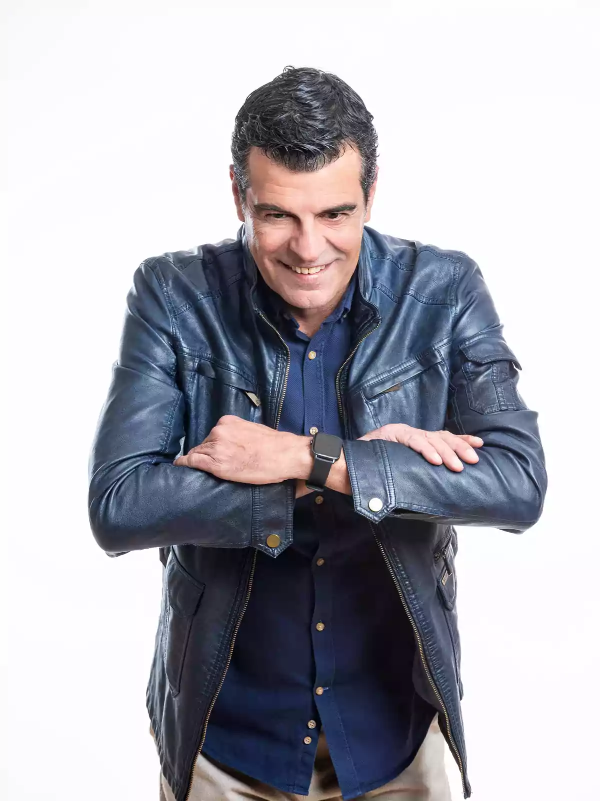 Hombre de mediana edad con chaqueta de cuero azul y camisa azul sonriendo con los brazos cruzados sobre el pecho Hombre de mediana edad con chaqueta de cuero azul y camisa azul sonriendo con los brazos cruzados sobre el pecho