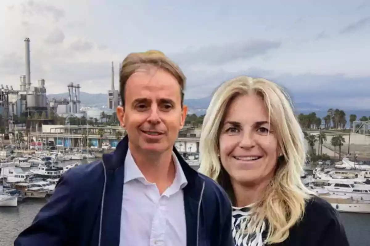 Dos personas posan frente a un puerto con barcos y una planta industrial al fondo