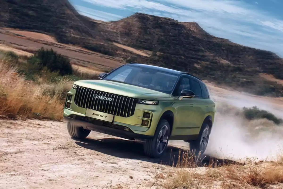 SUV verde circulando por un camino de tierra en un paisaje montañoso y soleado