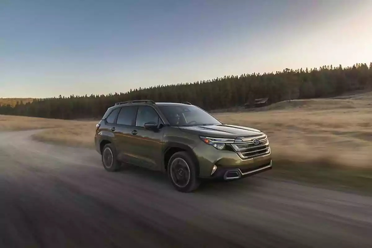 SUV color verde circulando por un camino de tierra en un paisaje natural al atardecer