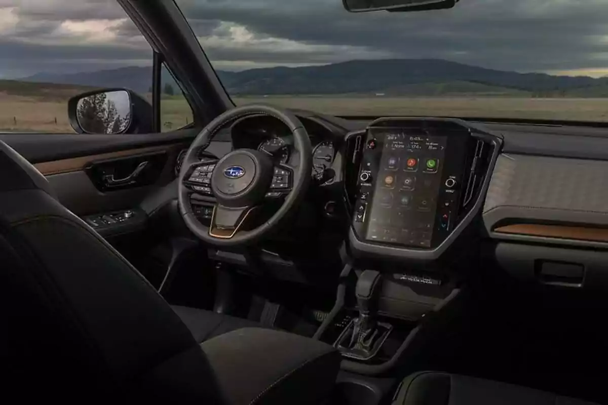 Interior moderno de un automóvil Subaru con pantalla táctil grande y vista panorámica hacia el campo a través de la ventana