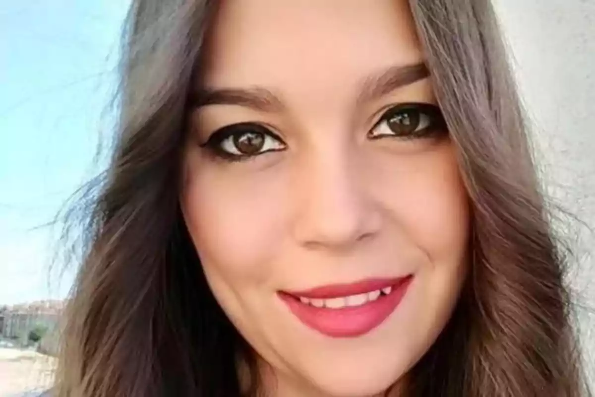 Mujer joven de cabello largo y castaño sonriendo frente a la cámara Mujer joven de cabello largo y castaño sonriendo frente a la cámara