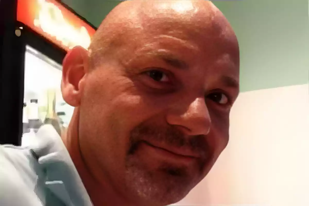 Hombre calvo de mediana edad sonriendo en un ambiente interior iluminado