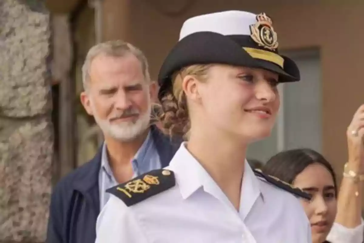 Young woman in a navy uniform smiles while an older man watches her in the background. Young woman in a navy uniform smiles while an older man watches her in the background.
