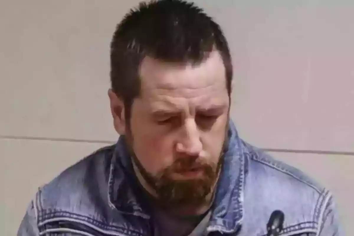 Hombre de cabello corto y barba con chaqueta de mezclilla mirando hacia abajo Hombre de cabello corto y barba con chaqueta de mezclilla mirando hacia abajo