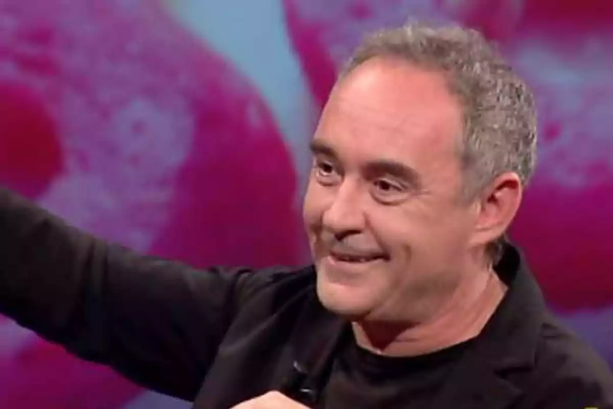 Hombre de cabello canoso y corto sonriendo y levantando el brazo en un ambiente con fondo rosa difuminado Hombre de cabello canoso y corto sonriendo y levantando el brazo en un ambiente con fondo rosa difuminado