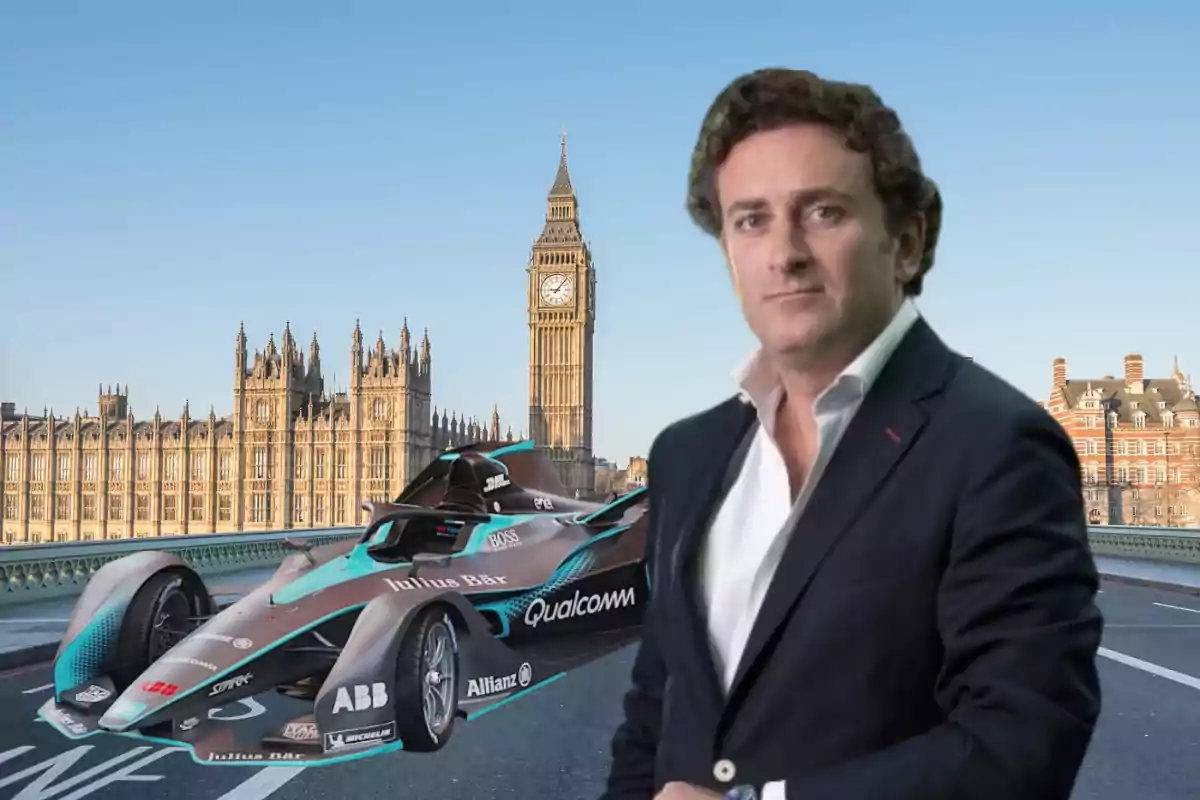 Hombre de cabello rizado con saco oscuro y camisa blanca posando frente a un auto de carreras eléctrico en un puente de Londres con el Big Ben y el Palacio de Westminster al fondo