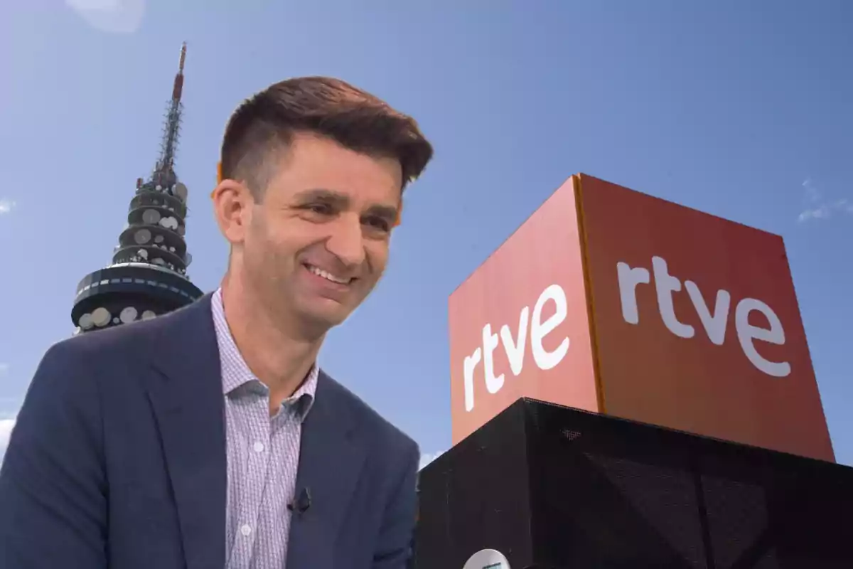 Hombre sonriente con chaqueta azul frente a un edificio de RTVE y una torre de telecomunicaciones bajo un cielo despejado