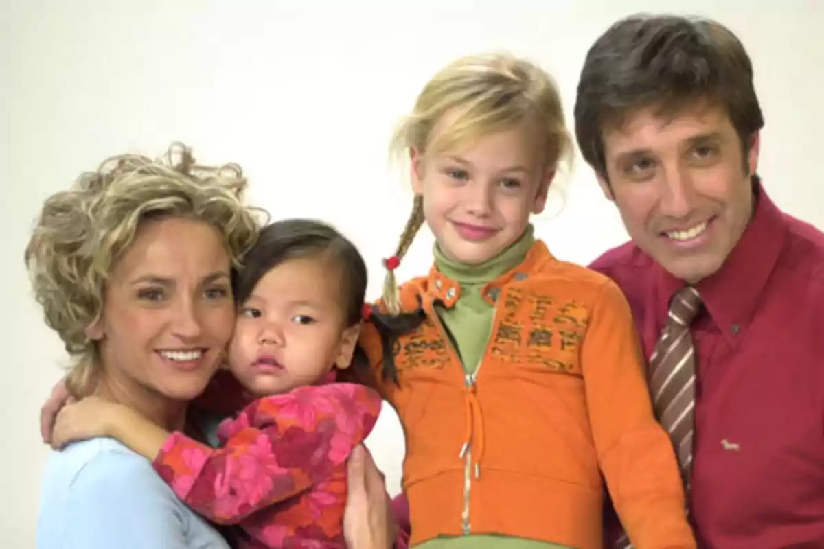 Familia de cuatro personas sonriendo y posando juntas frente a un fondo claro Familia de cuatro personas sonriendo y posando juntas frente a un fondo claro