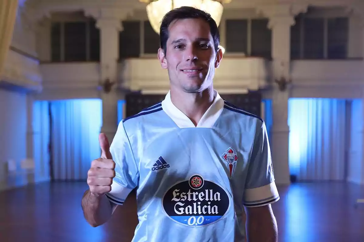 Jugador de fútbol con uniforme celeste del Celta de Vigo levantando el pulgar en señal de aprobación dentro de un salón elegante Jugador de fútbol con uniforme celeste del Celta de Vigo levantando el pulgar en señal de aprobación dentro de un salón elegante