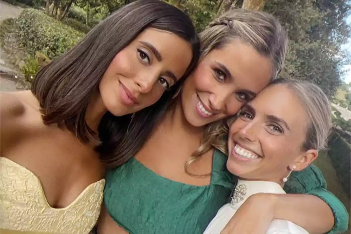 Tres mujeres sonríen abrazadas mientras posan para una selfie al aire libre en un entorno natural Tres mujeres sonríen abrazadas mientras posan para una selfie al aire libre en un entorno natural