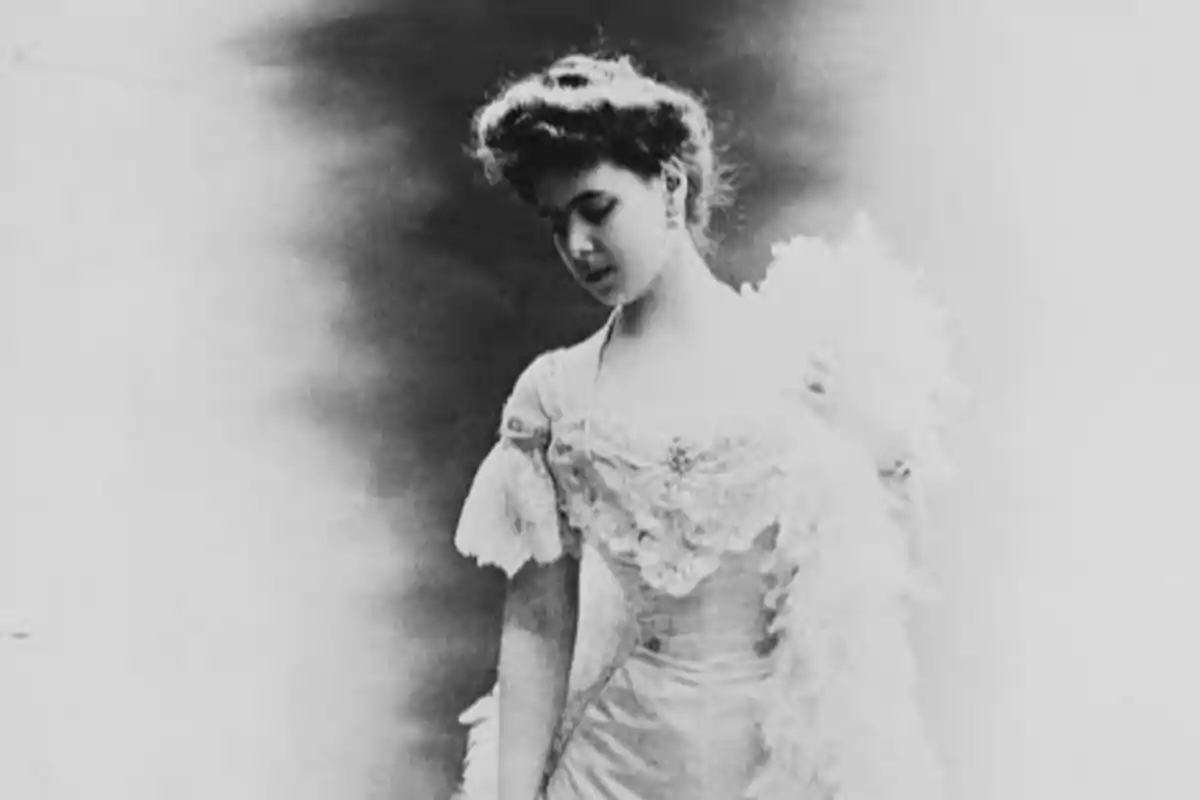 Mujer joven con vestido elegante de época mirando hacia abajo en una fotografía en blanco y negro Mujer joven con vestido elegante de época mirando hacia abajo en una fotografía en blanco y negro
