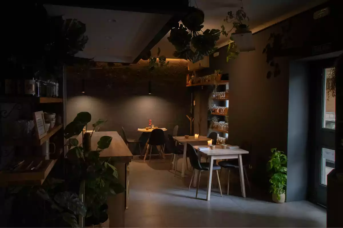 Restaurante acogedor con luz tenue, plantas decorativas y mesas de madera con velas encendidas Restaurante acogedor con luz tenue, plantas decorativas y mesas de madera con velas encendidas