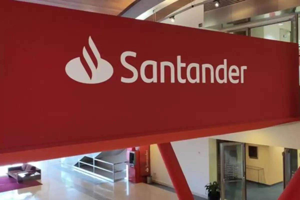 Letrero rojo con el logotipo y nombre de Santander en el interior de un edificio moderno Letrero rojo con el logotipo y nombre de Santander en el interior de un edificio moderno