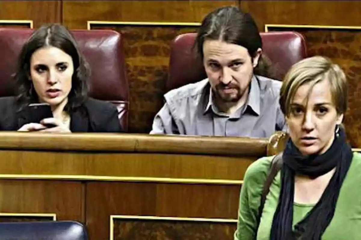 Tres personas en un recinto parlamentario dos sentadas en escaños y una de pie en primer plano Tres personas en un recinto parlamentario dos sentadas en escaños y una de pie en primer plano