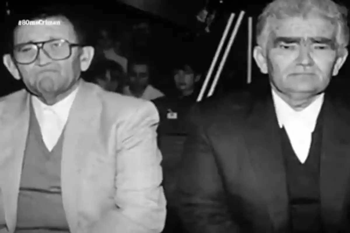 Dos hombres mayores vestidos con traje y suéter sentados uno junto al otro en una imagen en blanco y negro Dos hombres mayores vestidos con traje y suéter sentados uno junto al otro en una imagen en blanco y negro