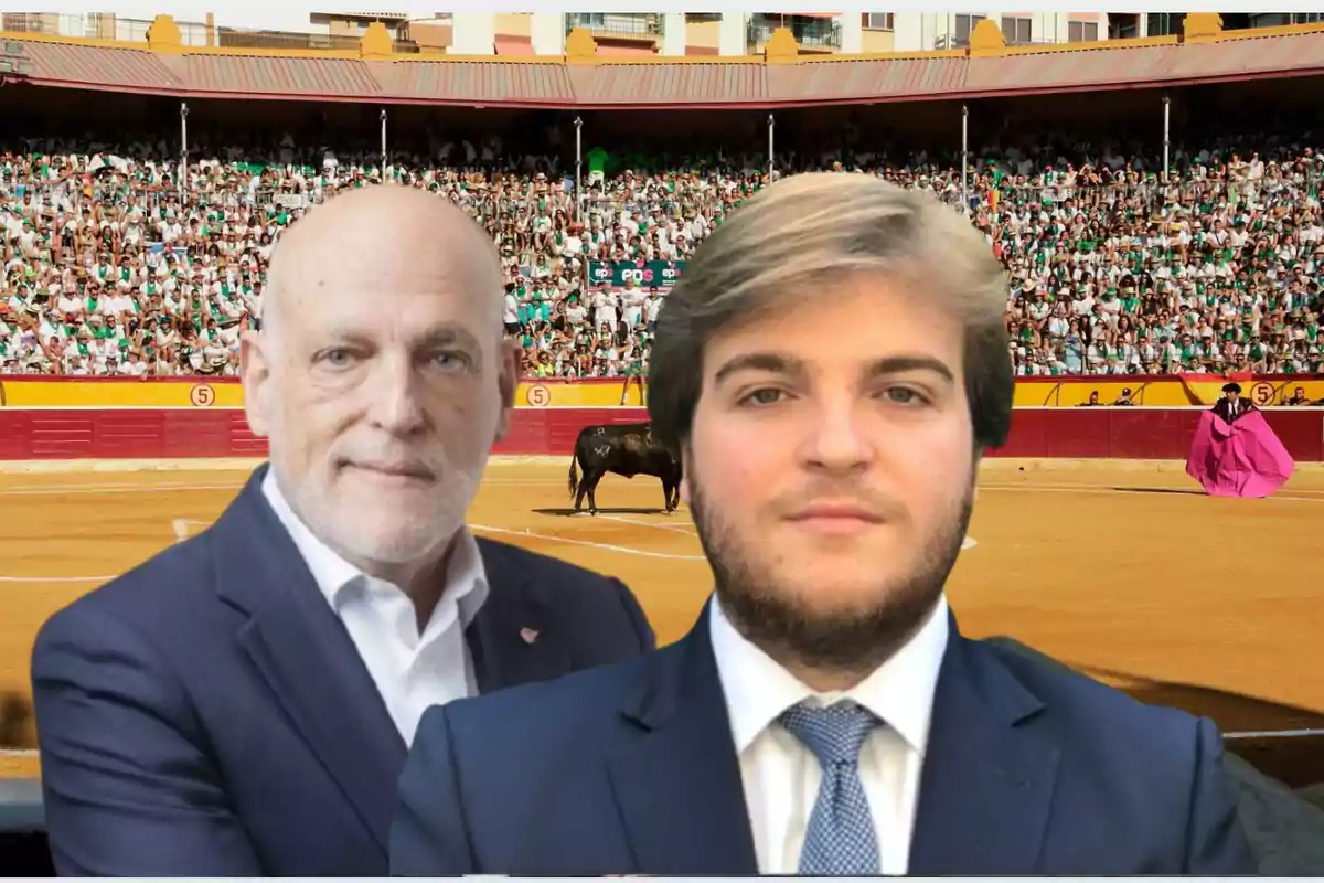 Dos hombres con traje posan en primer plano frente a una plaza de toros llena de público donde se realiza una corrida.
