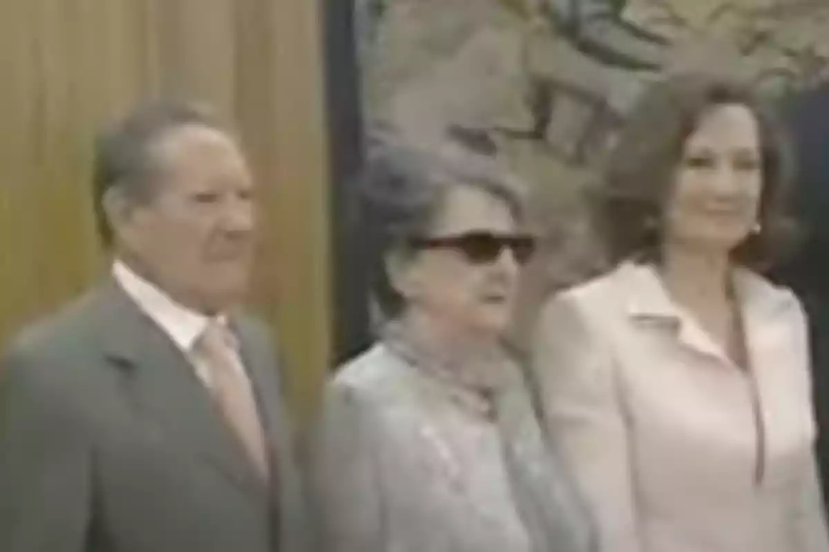 Tres personas posan juntas en un ambiente formal, dos mujeres y un hombre, todos vestidos elegantemente. Tres personas posan juntas en un ambiente formal, dos mujeres y un hombre, todos vestidos elegantemente.