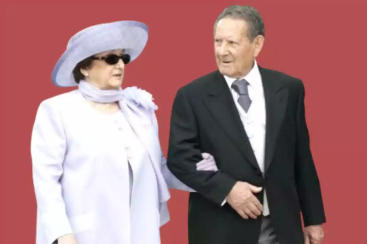 Pareja de personas mayores elegantemente vestidas caminando juntas sobre un fondo rojo Pareja de personas mayores elegantemente vestidas caminando juntas sobre un fondo rojo