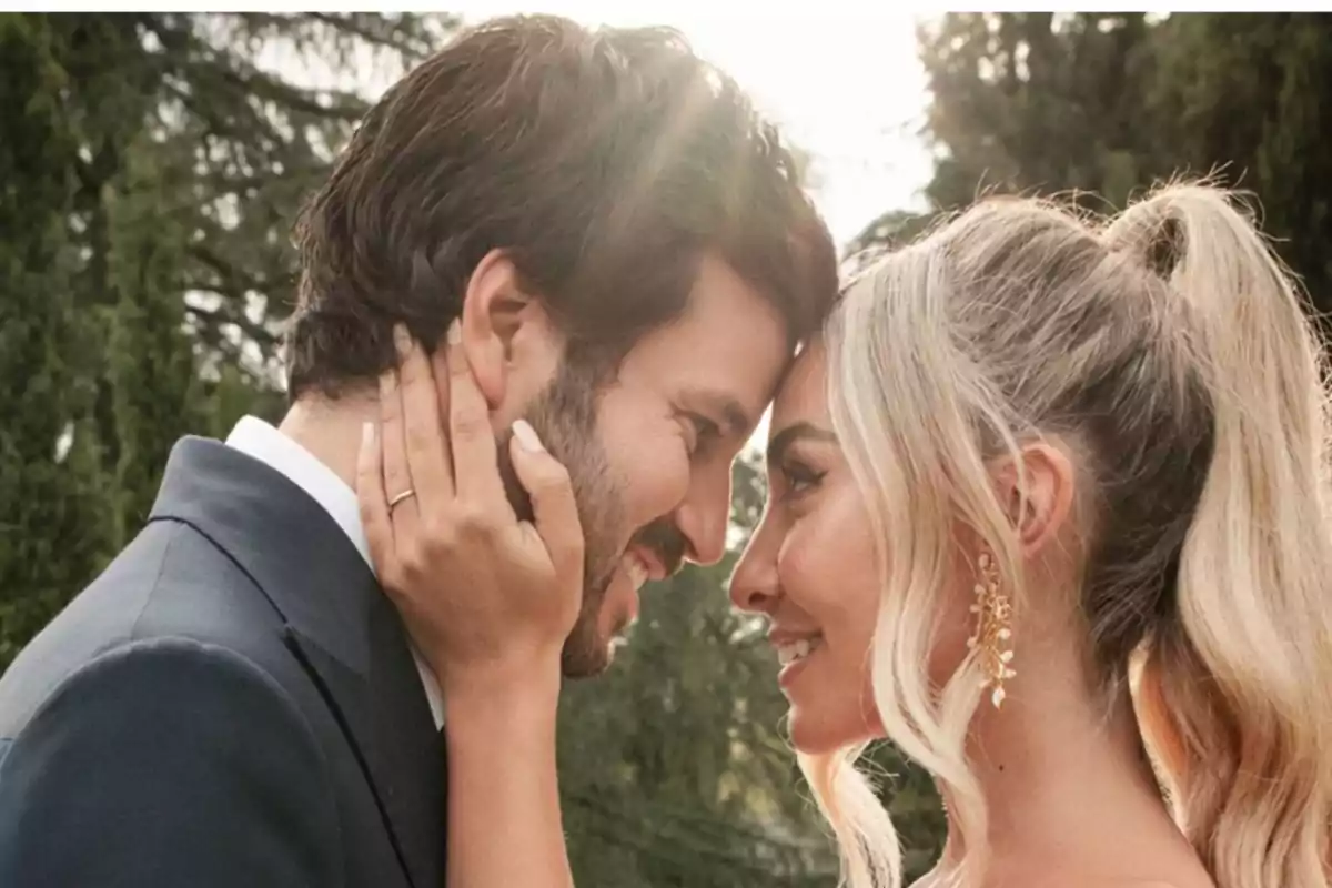 Pareja mirándose a los ojos y sonriendo en un entorno al aire libre con árboles de fondo Pareja mirándose a los ojos y sonriendo en un entorno al aire libre con árboles de fondo
