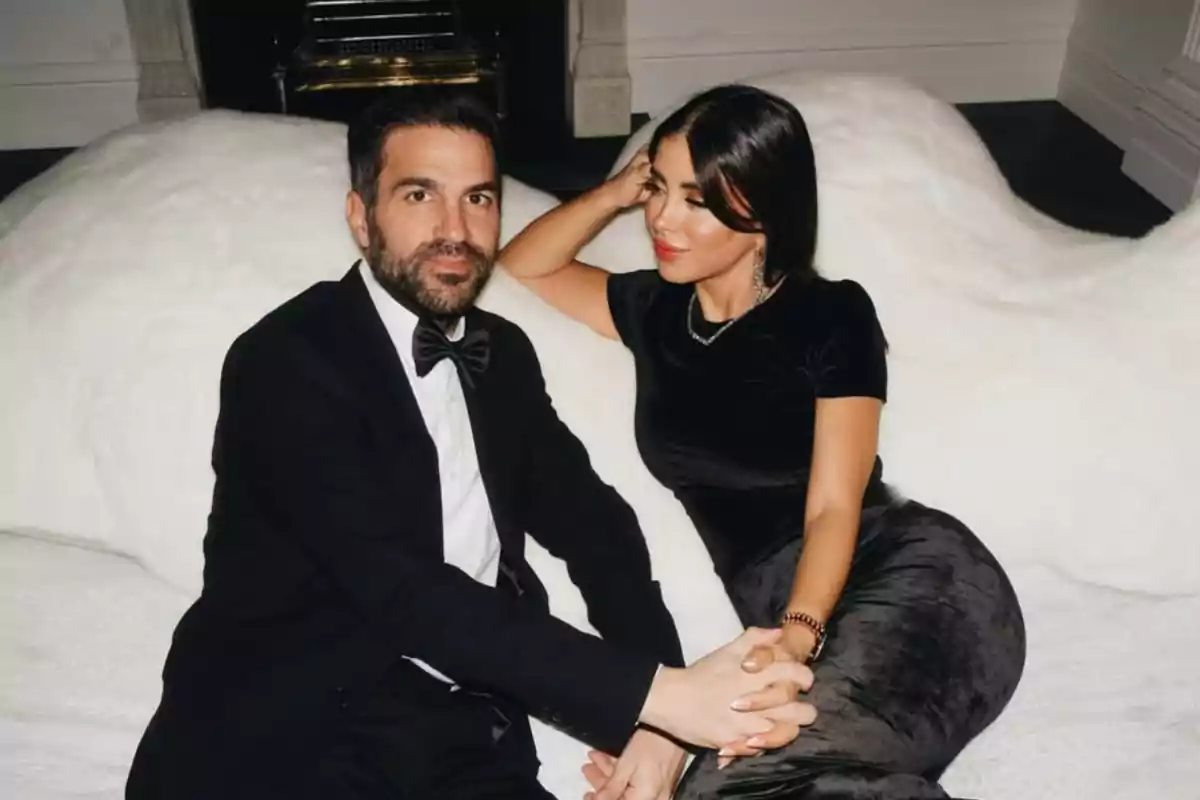 Pareja elegantemente vestida sentada en un sofá blanco tomados de la mano