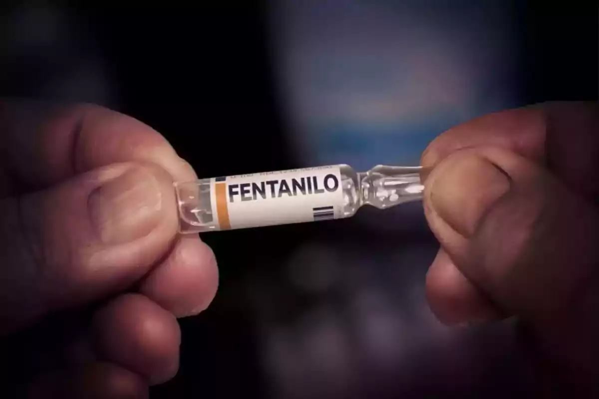 Manos sosteniendo una ampolleta de vidrio con la etiqueta que dice fentanilo