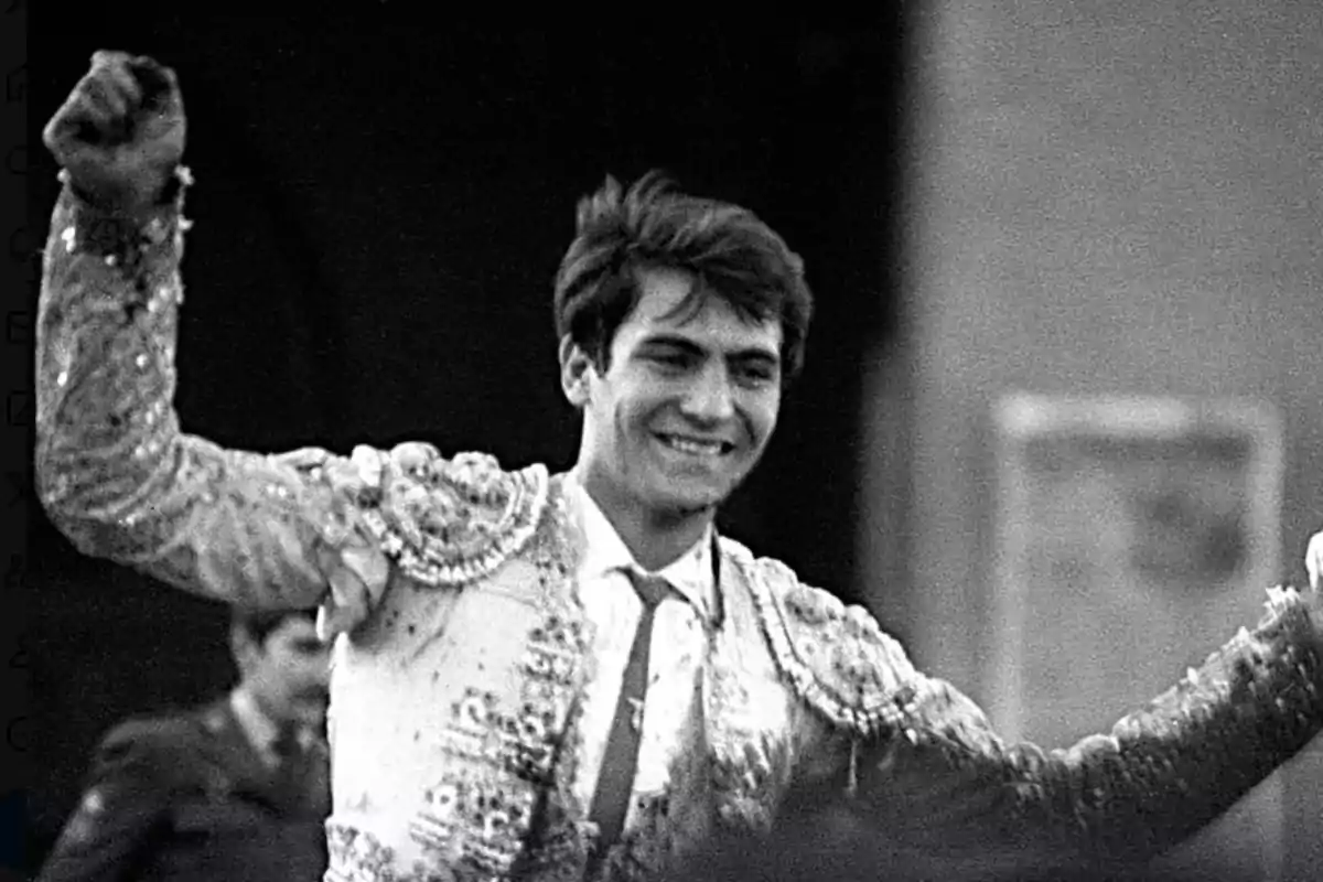 Un torero joven sonríe y levanta los brazos en señal de triunfo mientras viste un traje de luces en una imagen en blanco y negro Un torero joven sonríe y levanta los brazos en señal de triunfo mientras viste un traje de luces en una imagen en blanco y negro
