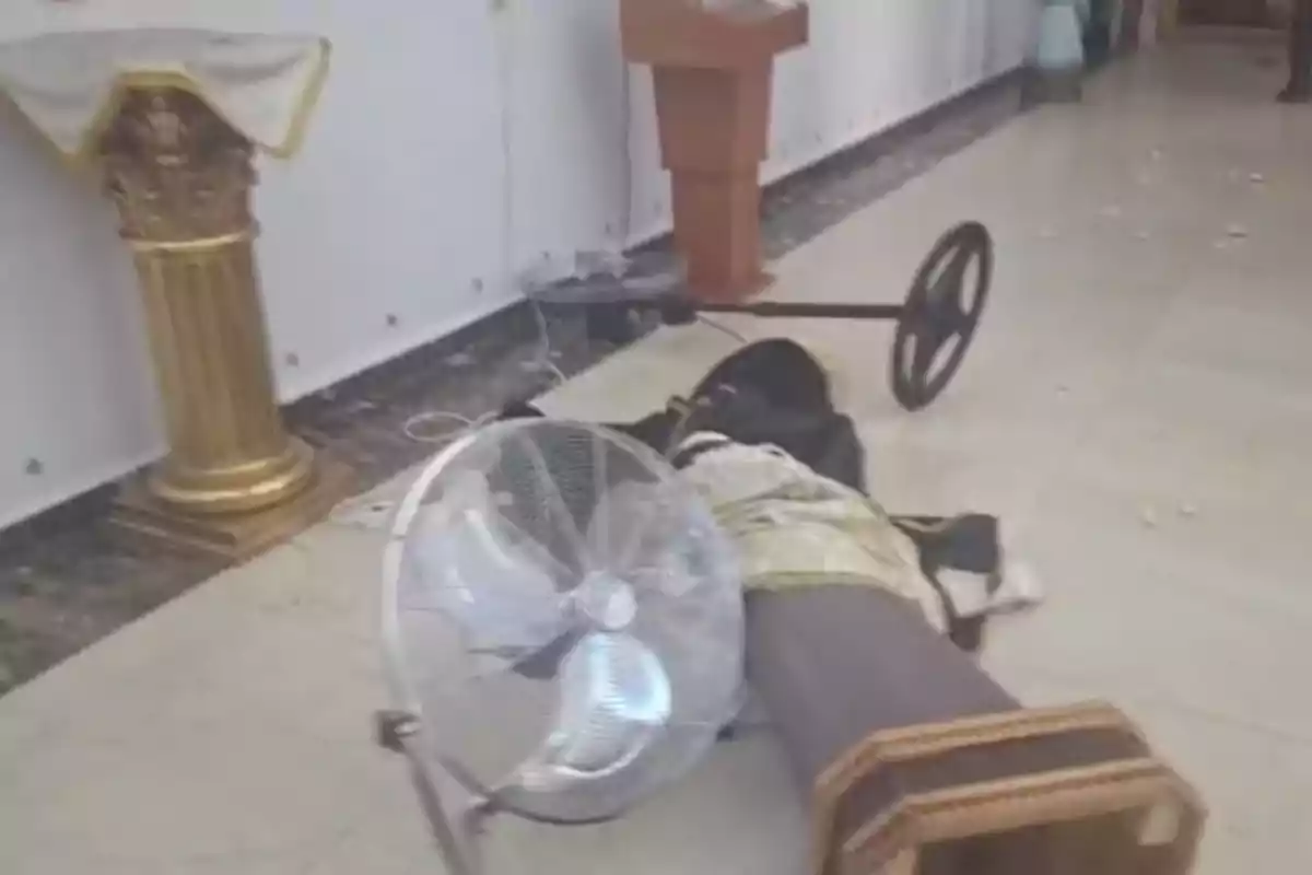 Una estatua religiosa caída en el suelo junto a un ventilador dentro de una iglesia. Una estatua religiosa caída en el suelo junto a un ventilador dentro de una iglesia.