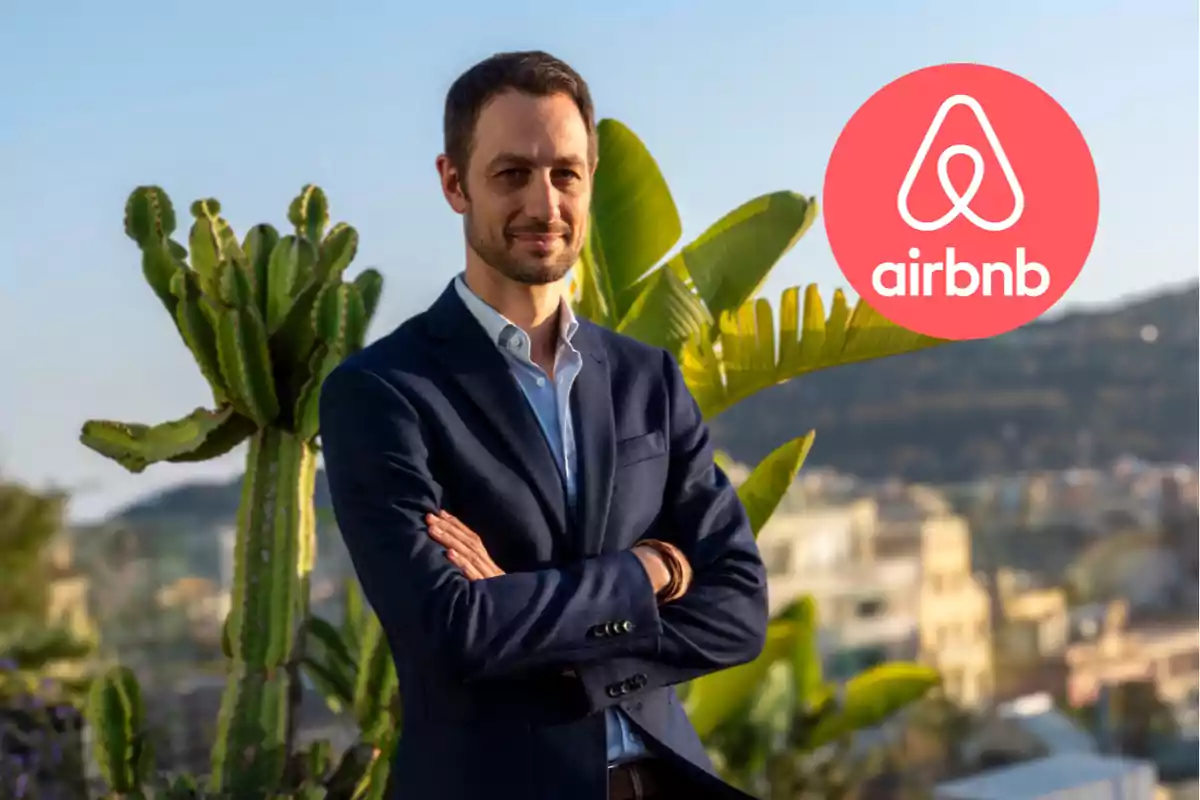 Hombre de traje azul posando con los brazos cruzados frente a plantas y paisaje urbano con el logo de Airbnb en la esquina superior derecha
