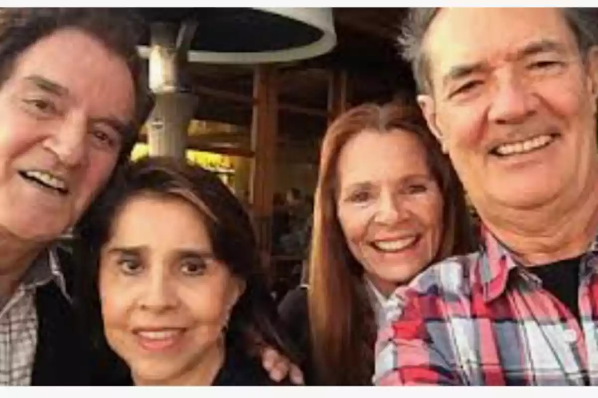 Cuatro personas adultas sonríen mientras posan juntas para una selfie en un ambiente al aire libre Cuatro personas adultas sonríen mientras posan juntas para una selfie en un ambiente al aire libre