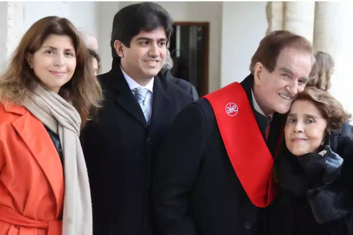 Cuatro personas posan sonrientes en un evento formal, una de ellas lleva una banda roja sobre los hombros Cuatro personas posan sonrientes en un evento formal, una de ellas lleva una banda roja sobre los hombros