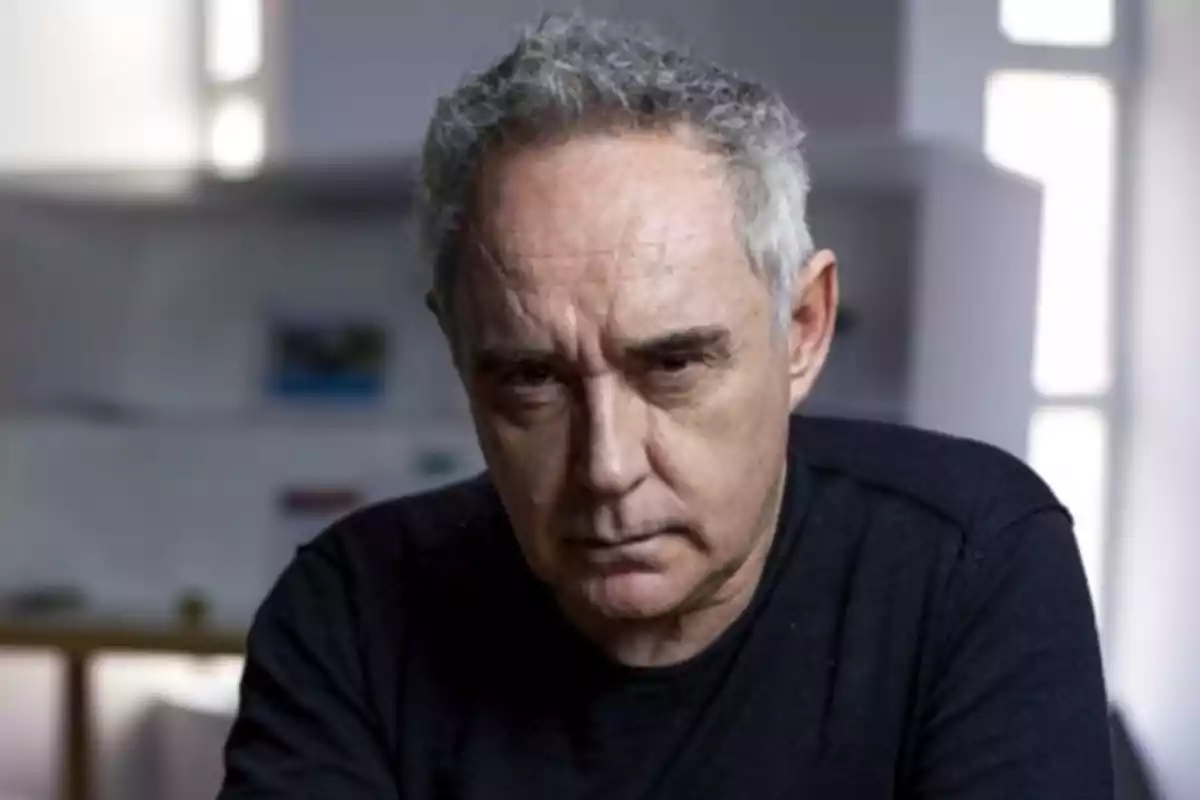 Hombre de cabello canoso y expresión seria vistiendo camiseta oscura en un ambiente interior iluminado