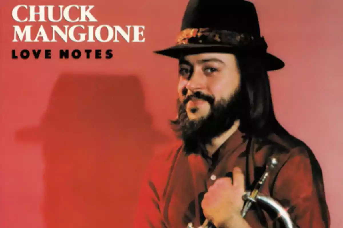 Portada del álbum Love Notes de Chuck Mangione con fondo rojo y el músico sosteniendo un instrumento de metal mientras sonríe y lleva sombrero negro Portada del álbum Love Notes de Chuck Mangione con fondo rojo y el músico sosteniendo un instrumento de metal mientras sonríe y lleva sombrero negro