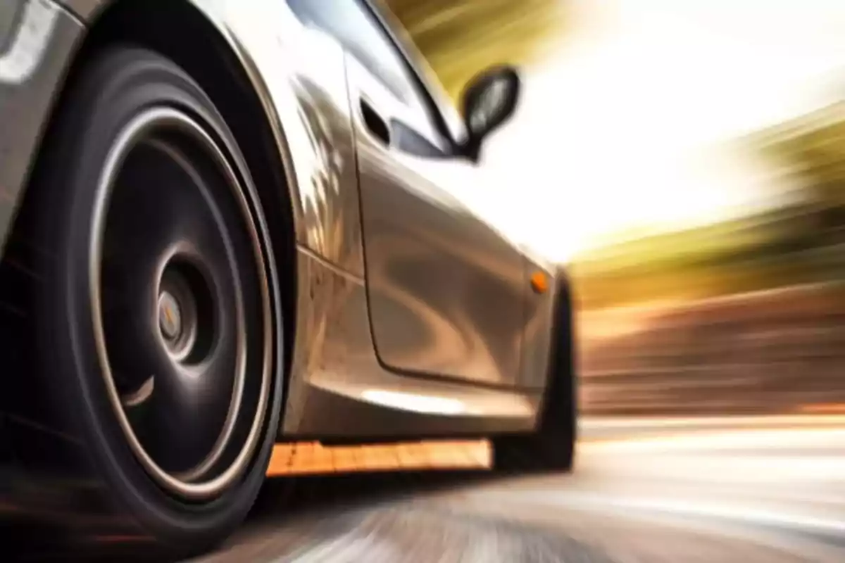 Auto deportivo plateado en movimiento visto desde un ángulo bajo con efecto de velocidad y fondo desenfocado Auto deportivo plateado en movimiento visto desde un ángulo bajo con efecto de velocidad y fondo desenfocado