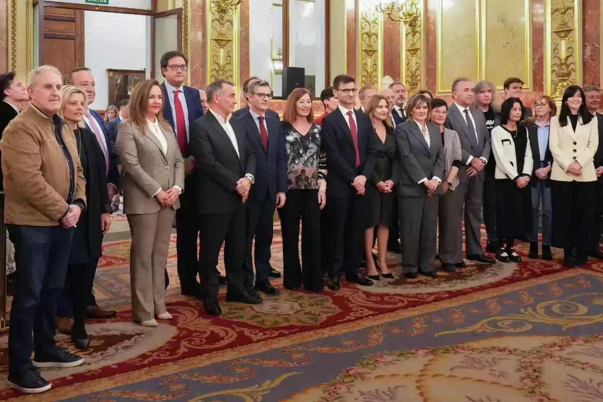 Un grupo de personas posando para una foto en un elegante salón decorado con alfombra y paredes doradas Un grupo de personas posando para una foto en un elegante salón decorado con alfombra y paredes doradas