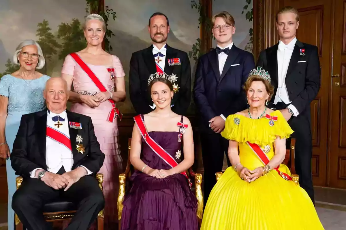 Un grupo de personas elegantemente vestidas posando en una sala decorada, algunas de ellas llevan bandas, medallas y coronas Un grupo de personas elegantemente vestidas posando en una sala decorada, algunas de ellas llevan bandas, medallas y coronas