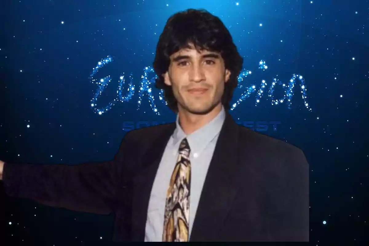 Hombre joven con cabello oscuro y traje posando frente a un fondo azul con la palabra Eurovision formada por estrellas. Hombre joven con cabello oscuro y traje posando frente a un fondo azul con la palabra Eurovision formada por estrellas.