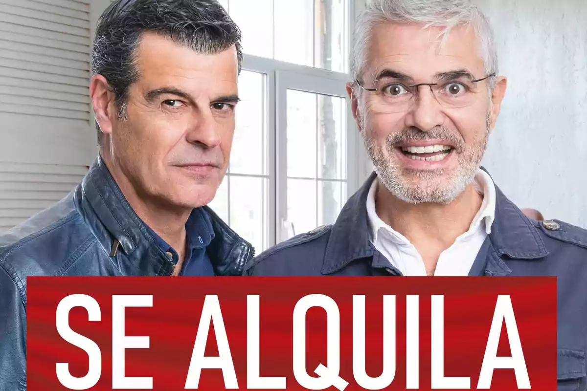 Dos hombres posan juntos frente a una ventana con un letrero rojo que dice SE ALQUILA en letras grandes blancas Dos hombres posan juntos frente a una ventana con un letrero rojo que dice SE ALQUILA en letras grandes blancas