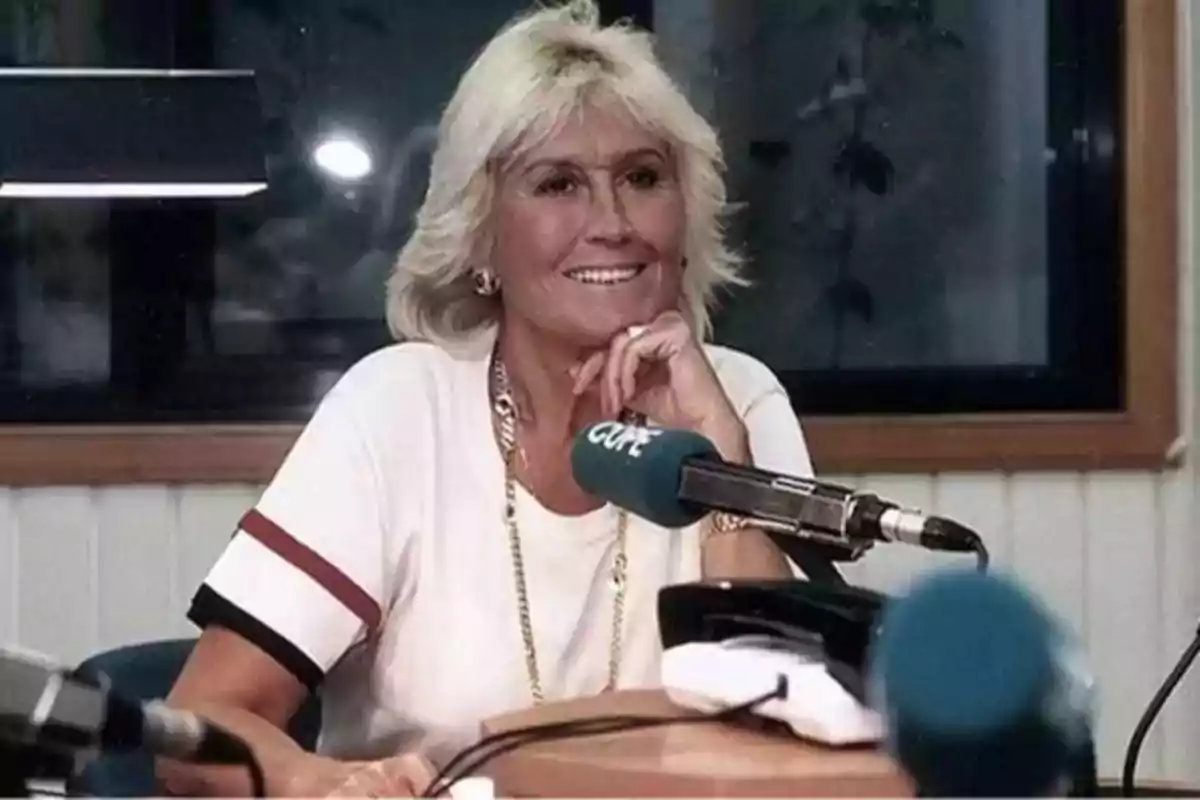 Mujer rubia sonriente sentada frente a un micrófono en una cabina de radio Mujer rubia sonriente sentada frente a un micrófono en una cabina de radio