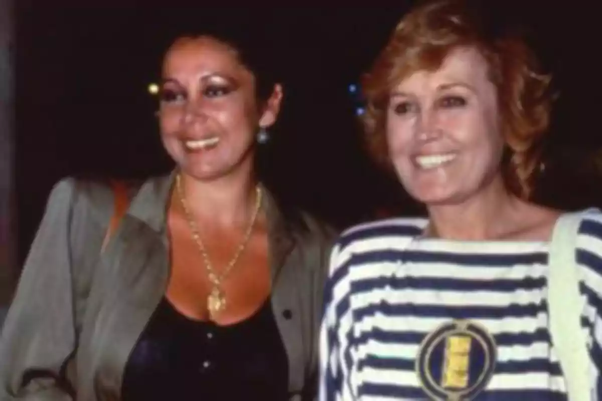 Dos mujeres sonríen mientras posan juntas en una fotografía tomada en un ambiente nocturno Dos mujeres sonríen mientras posan juntas en una fotografía tomada en un ambiente nocturno