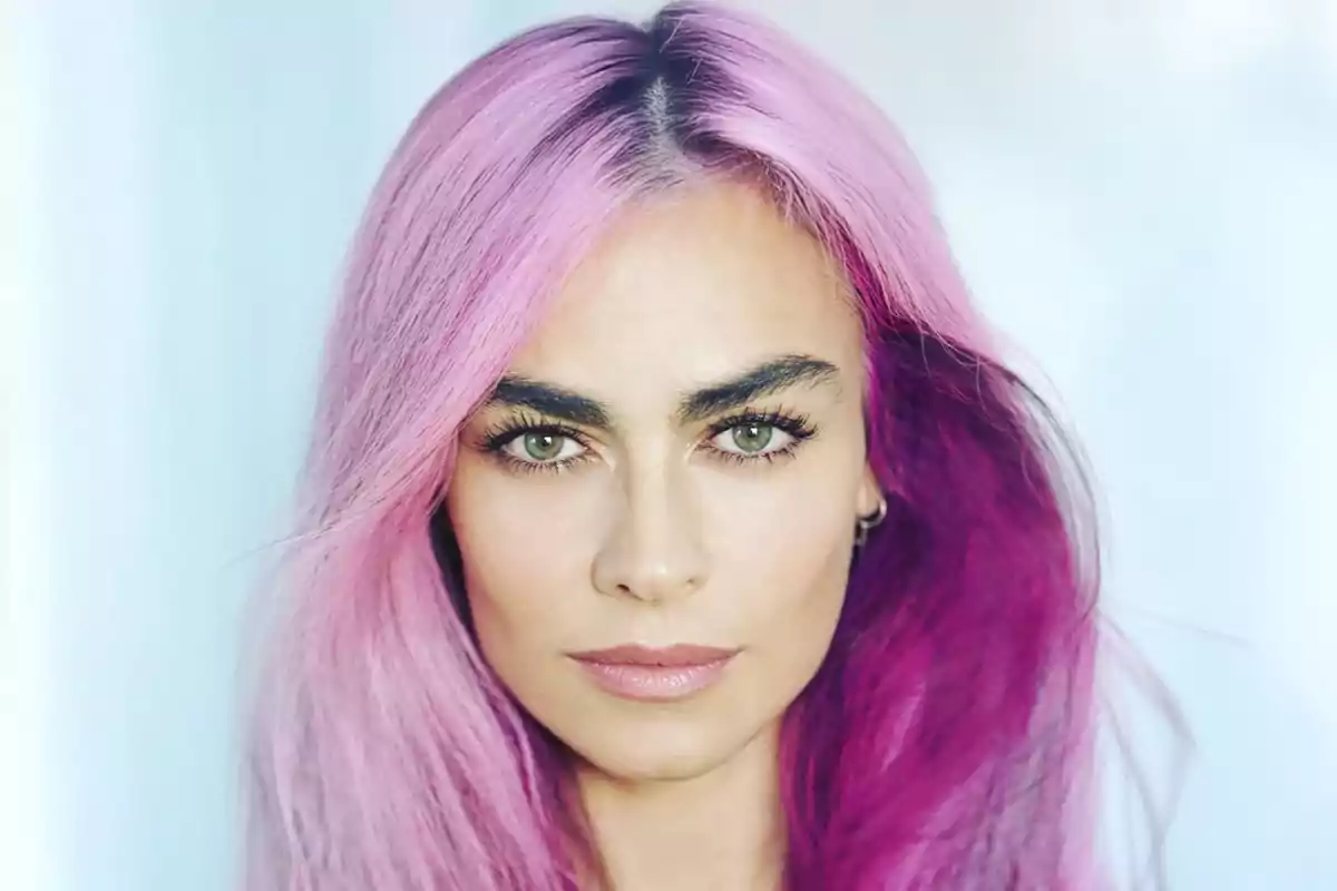 Mujer de cabello largo teñido de rosa y morado mirando al frente con expresión seria Mujer de cabello largo teñido de rosa y morado mirando al frente con expresión seria