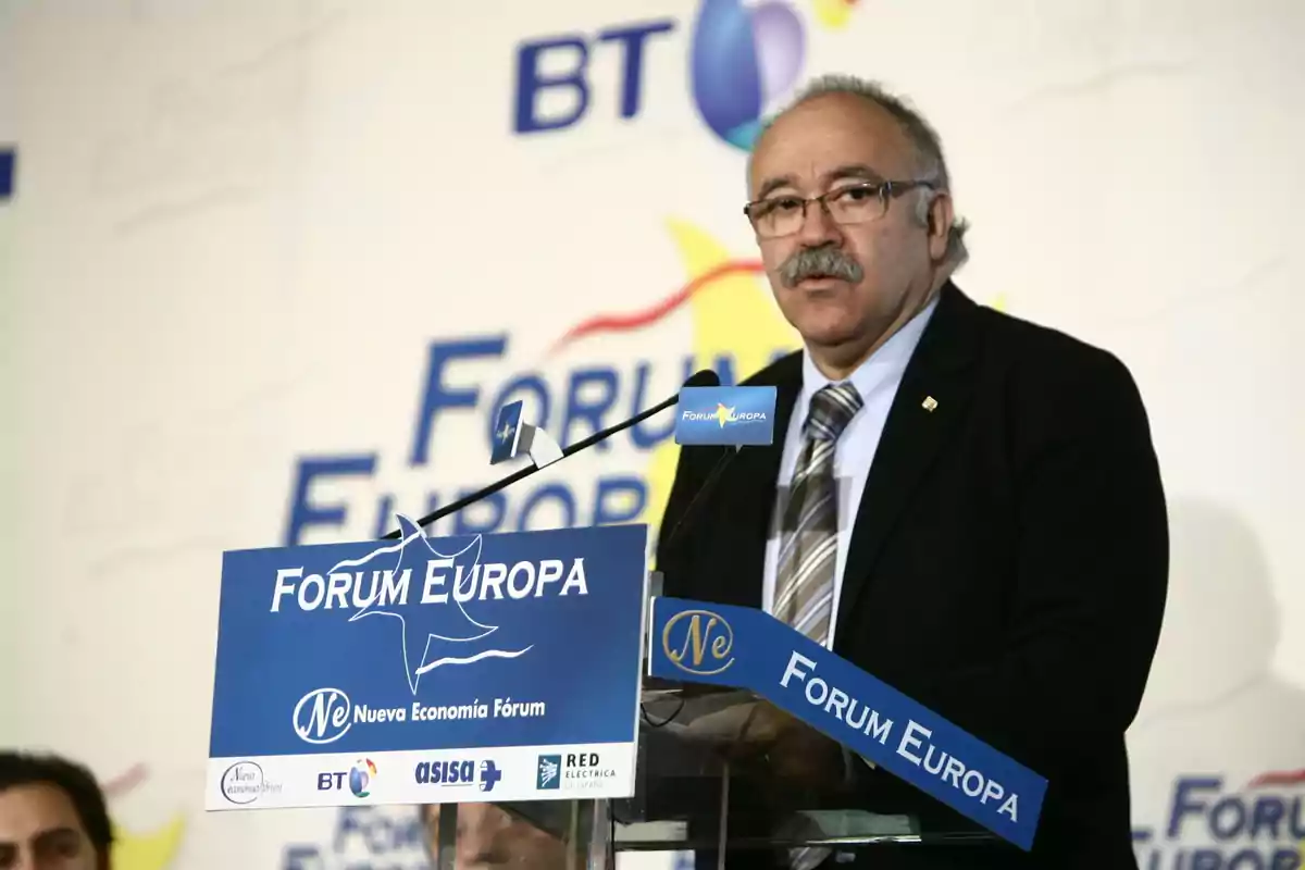 Hombre de bigote y gafas hablando en un atril azul durante un evento del Forum Europa Hombre de bigote y gafas hablando en un atril azul durante un evento del Forum Europa