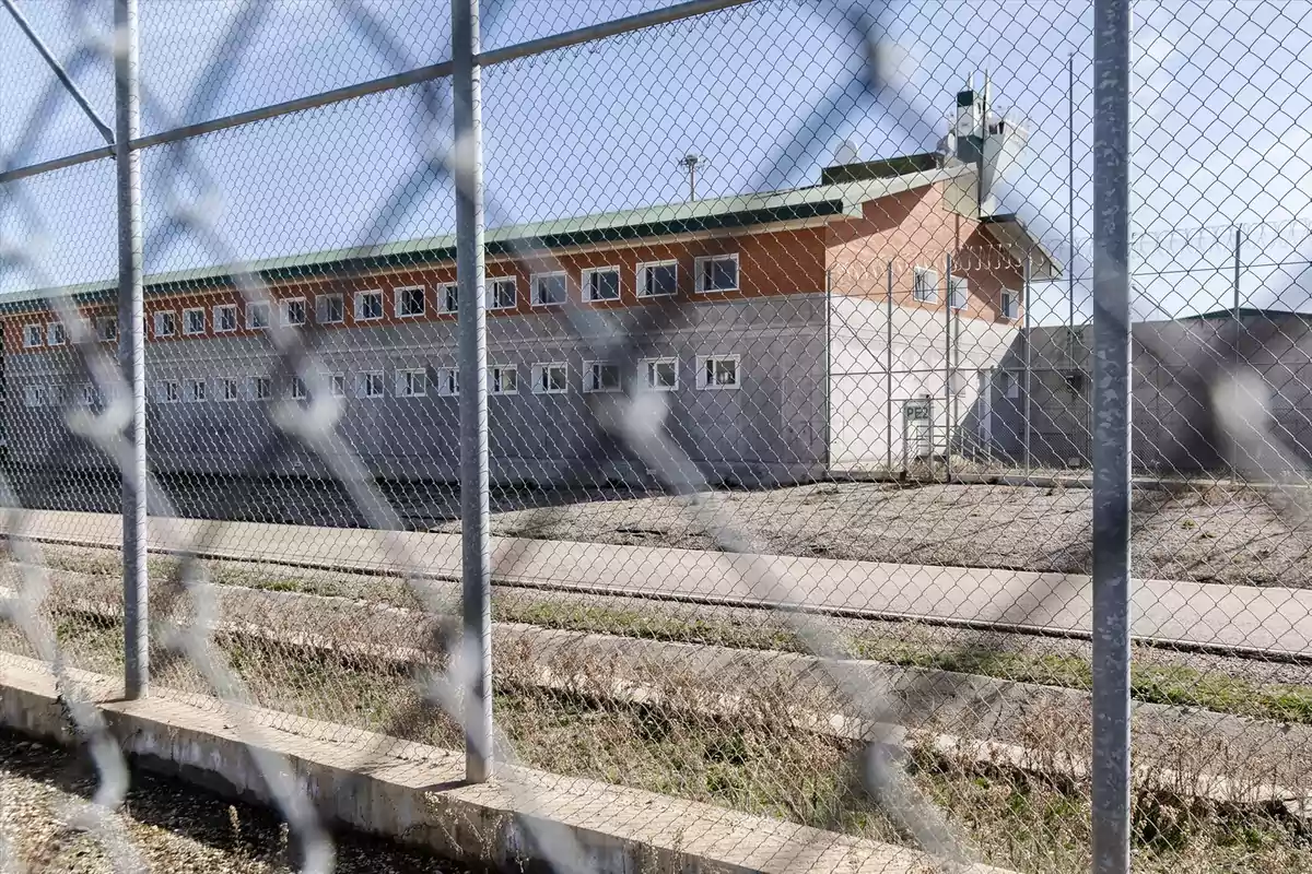 Edificio de una prisión visto a través de una cerca de malla metálica Edificio de una prisión visto a través de una cerca de malla metálica