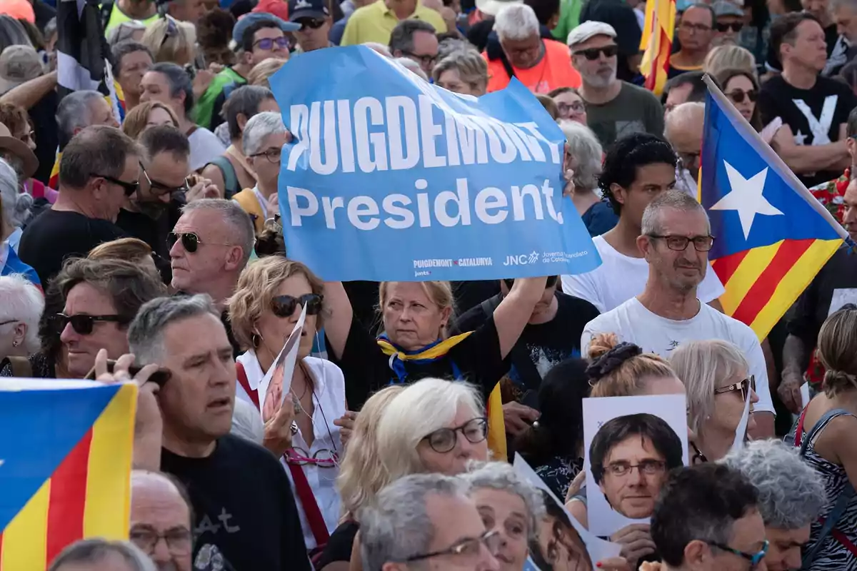 Manifestación con personas sosteniendo pancartas de apoyo a Puigdemont y banderas independentistas catalanas