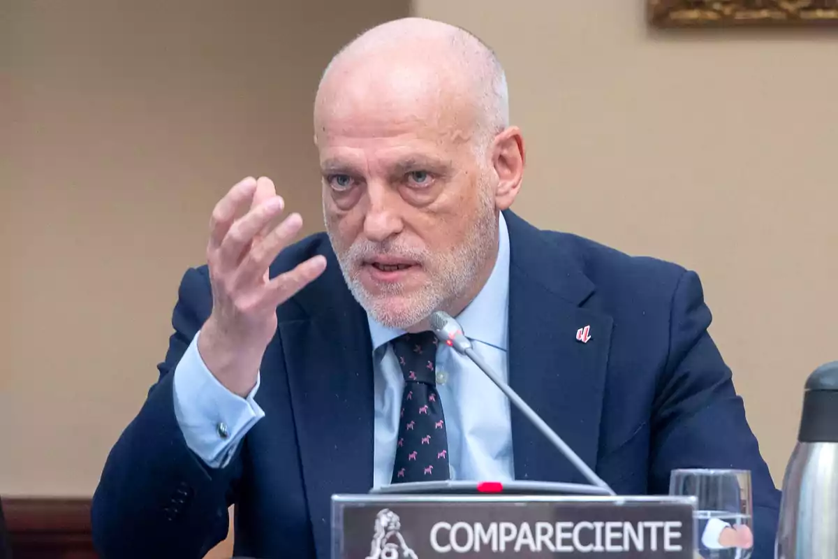 Hombre calvo de barba canosa hablando en una comparecencia oficial con gesto serio y la mano levantada frente a un micrófono Hombre calvo de barba canosa hablando en una comparecencia oficial con gesto serio y la mano levantada frente a un micrófono