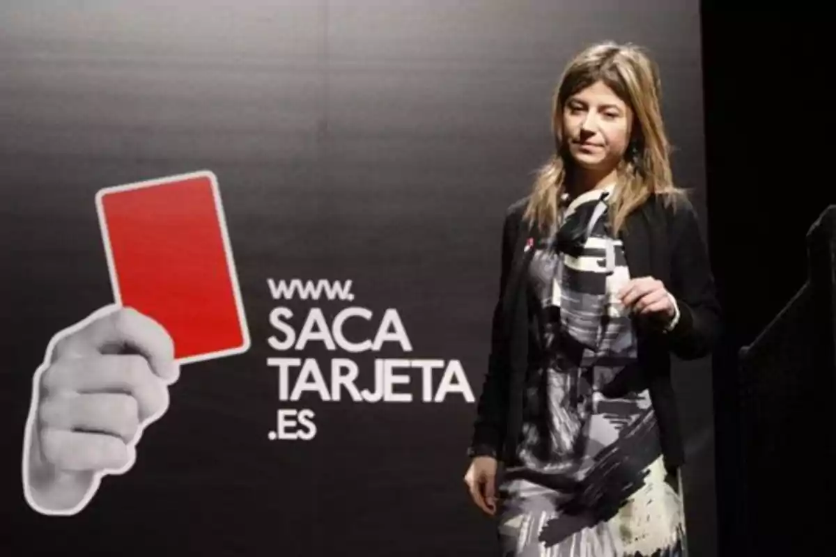 Mujer de pie junto a un cartel negro con una mano sosteniendo una tarjeta roja y el texto www.sacatarjeta.es Mujer de pie junto a un cartel negro con una mano sosteniendo una tarjeta roja y el texto www.sacatarjeta.es