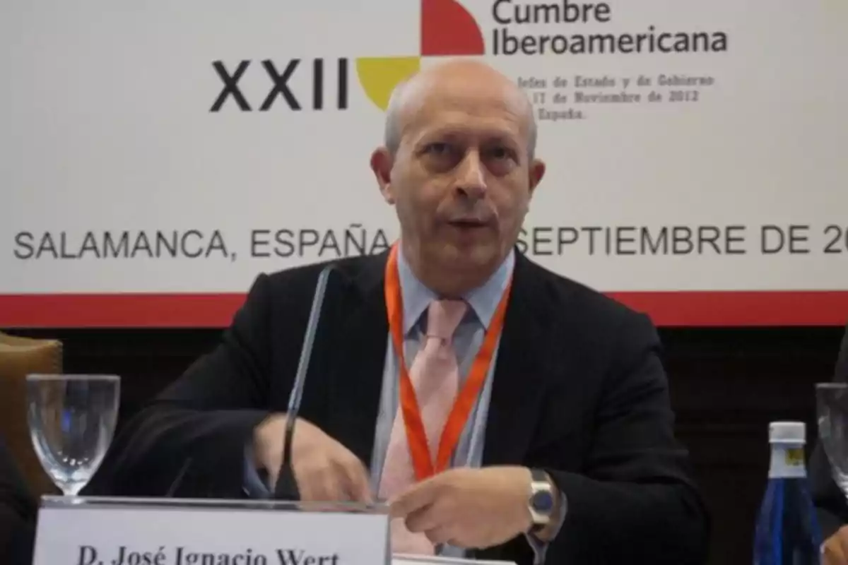 Hombre calvo con traje y corbata rosa sentado en una mesa durante una conferencia en la Cumbre Iberoamericana en Salamanca España Hombre calvo con traje y corbata rosa sentado en una mesa durante una conferencia en la Cumbre Iberoamericana en Salamanca España